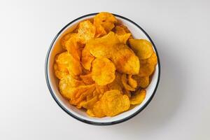 Smoked paprika potato chips in bowl on white background. Fast food, junk food and unhealthy snacks concept. Top view, copy space photo