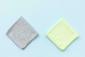 Two new folded microfiber cloth for cleaning on blue background. Cleaning micro fabric towels for dusting and polishing. Domestic household cleaning service concept. Top view, copy space photo