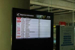 Flight information display system showing airline schedule. Yogyakarta International Airport YIA is a modern facility serving international and domestic flights. Kulon Progo - Indonesia 09 03 2023 photo