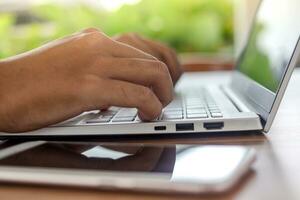 Close up of male hand typing on laptop keyboard. Freelance working at cafe, enjoying the surroundings photo