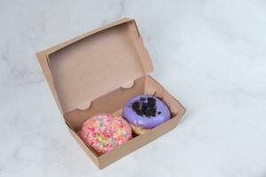 Delicious sweet donuts with different flavors in small paper box. Isolated image on white background photo