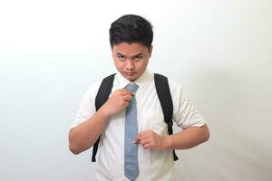 Indonesian senior high school student wearing white shirt uniform with gray tie adjusting his necktie. Isolated image on white background photo