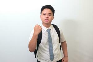 Indonesian senior high school student wearing white shirt uniform with gray tie trying to punch with fist. Bullying concept. Isolated image on white background photo