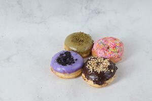 Delicious sweet donuts with different flavors on a table. Isolated image on white background photo