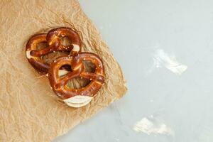 Two homemade freshly baked soft pretzels on brown paper. Traditional Bavarian pretzel for Octoberfest. Top view, copy space photo