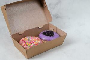 Delicious sweet donuts with different flavors in small paper box. Isolated image on white background photo