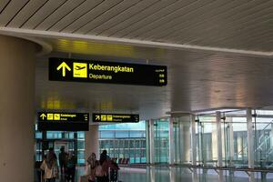 Directional sign at the airport as information for passengers. Yogyakarta International Airport YIA is modern facility serving international and domestic flights. Kulon Progo - Indonesia 09 03 2023 photo