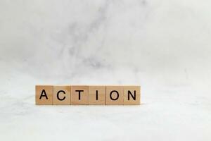 Top view of Action word on wooden cube letter block on white background. Business concept photo