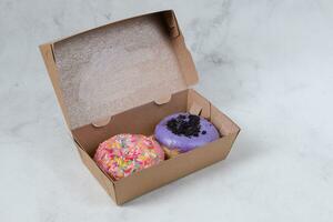 Delicious sweet donuts with different flavors in small paper box. Isolated image on white background photo