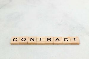 Top view of contract word on wooden cube letter block on white background. Business concept photo