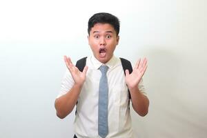 Indonesian senior high school student wearing white shirt uniform with gray tie covering his face with hands. Isolated image on white background photo