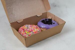 Delicious sweet donuts with different flavors in small paper box. Isolated image on white background photo