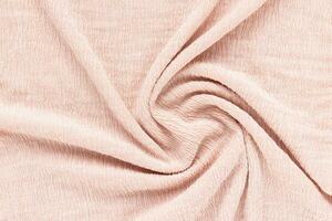 Soft pink fabric with puckered texture twisted in spiral. Abstract background. Fashion and clothes design trends concept photo
