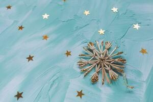 Christmas diy decoration snowflakes and gold stars confetti on cyan backround. Winter holidays concept. Flat lay, copy space, top view, social media hero header template photo