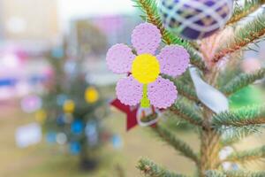 Handmade plastic pink flower decoration on Christmas tree outdoors. Creative ideas for children. Environment, recycle, reuse, upcycling and zero waste concept. Selective focus, no snow background photo