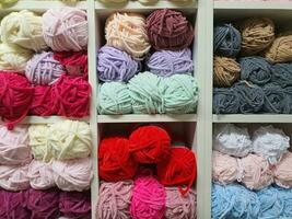 vistoso hilos o pelotas de diferente tipos de lana para tejido de punto en estantería en el mercería tienda. tejido artesanía concepto foto
