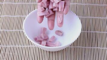 Female hand placing raw ham cubes on white ceramic bowl video