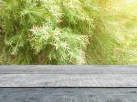 Wooden table, green bushes in the background  sunlight shines  There is space to display your products. photo