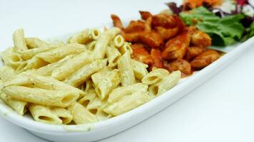 cooked pasta, chicken and fresh salad on a plate on white background video