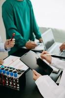 Medical team having a meeting with doctors in white lab coats and surgical scrubs seated at a table discussing a patients working online using computers in the medical industry photo