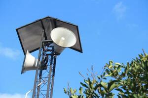 mosque loudspeakers on a post on a rooftop for playing the Islamic call to prayer in front of the city skyline photo