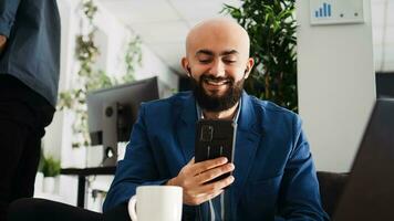 Businessman on online videoconference, talking to executive board on briefing meeting. Middle eastern office employee working with online telework call on mobile phone. Tripod shot. photo