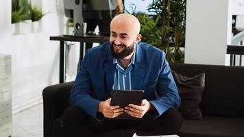 Businessman solving company problems on tablet, looking at online statistics or analytics in open space office. Entrepreneur developing successful software, working on startup plan. Handheld shot. photo