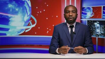 News presenter covering daily topics live on tv program, hosting entertainment and media segment in studio. African american journalist doing reportage of breaking news on global television network. photo