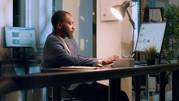 Registrar focused on checking online company documents for mismatching values during nightshift. Employee in office paying attention to paperwork figures, verifying accuracy photo