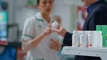 Close up shot of pharmaceutical pill bottles on apothecary shelves with druggist helping customer in blurry background. Medicinal products in chemist store ready to be purchased by clients photo