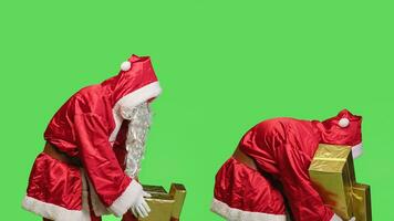 hombre retratar Papa Noel con bolso lleno de regalos y regalos, que lleva cajas decorado con cintas para niños alrededor el globo. padre Navidad extensión fiesta espíritu, pantalla verde. foto