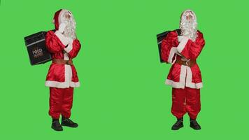 Santa claus in red suit with backpack working as deliveryman during christmas eve, full body greenscreen backdrop. Saint nick cosplay delivering fast food order for winter holidays. photo