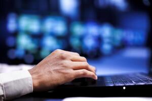 Close up shot of employee in server farm using laptop to set up configuration management tools that enable automatic failover and load balancing, preventing supercomputers system crash photo