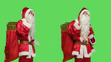 Santa claus cosplay shows marketing ad against greenscreen backdrop, posing with bag of gifts to advertise winter holiday season with main character. Father christmas red costume. photo