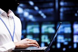 Employee using laptop to do checkup on supercomputers with high computing power enabling hyperscale server farm to support demanding applications, including AI and machine learning workloads photo