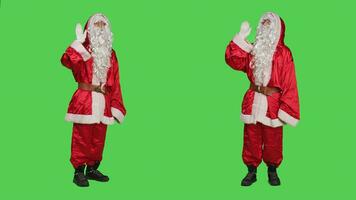 simpático personaje ola y saludar personas en cámara, vistiendo tradicional festivo disfraz a untado Navidad espíritu. joven adulto vestido como Papa Noel claus diciendo Hola, pantalla verde fondo. foto
