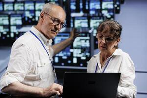 Licensed electricians working to maintain uptime in high tech establishment. Qualified wiremen brainstorming solutions to data center server rows crashing, trying to fix components photo