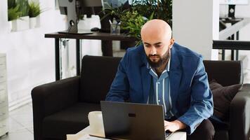 Middle eastern man reviews data to increase profit with new small business growth strategy, working in office. Professional analyst checks reports and statistics in coworking space. Tripod shot. photo