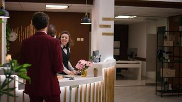 Businessman rings service bell in lobby to call for hotel concierge personnel and receive assistance at check in. Professional arriving at resort and asking about amenities during work trip. photo