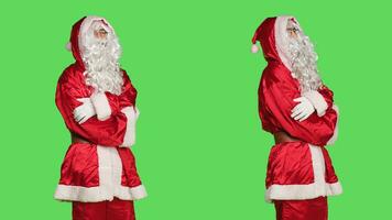 Man dressed in santa claus costume with fluffy white beard, stands against greenscreen backdrop. Character cosplay ready to spread winter holiday spirit, person portraying december happiness. photo