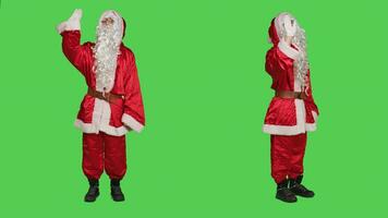 Cheerful character waving hello on camera, greeting people and spreading christmas positivity. Santa claus saying hi while he is wearing iconic red costume with hat and white beard. photo