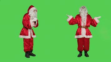 Santa claus praying to god with hands in a prayer, posing over full body greenscreen in studio. Spiritual religious character with festive red suit, talking to jesus advertising christmas holiday. photo