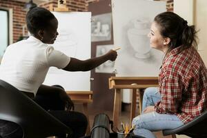 dos contento joven mujer amigos aprendizaje nuevo cosas juntos, asistiendo grupo Arte clase, que se discute obra de arte y sonriente. joven diverso personas hablando comunicado durante dibujo clase para adultos foto