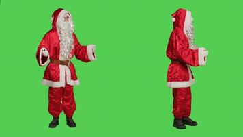 Father christmas celebrating holiday with iconic festive costume and white beard, standing against greenscreen backdrop. Joyful adult saying ho ho ho in studio, santa claus character. photo