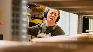 Female worker dancing and verifying list in depot, having fun with music and dance moves while she works with merchandise. Young employee examining delivery logistics in warehouse. photo