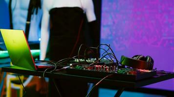 DJ mixing station on stage at club, empty discotheque and dance floor with audio stereo panel used for entertainment. Nightclub with discolights and electronic music used for clubbing. photo