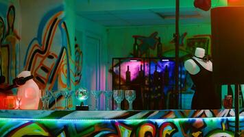 Multiple alcoholic drinks on bar at underground funky party, empty dance floor at nightclub. Discotheque prepared for dancing event with DJ mixing performance and live music show. photo