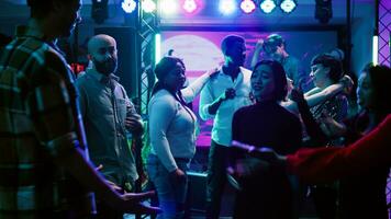 Young partners dancing together at club, enjoying slow music to dance in pairs. Romantic couples having fun with friends at social gathering clubbing event, attending modern party. Handheld shot. photo