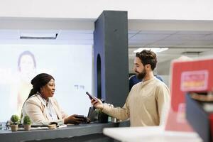 Young man standing at retail checkout counter holding smartphone paying for purchases, using nfc technology to pay for clothes while shopping in clothing store, customer making contactless payment photo