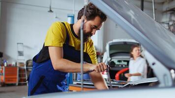 Licensed repairman in car service using torque wrench to tighten bolts after replacing engine. Garage worker uses professional tools to fix client automobile, extreme close up photo